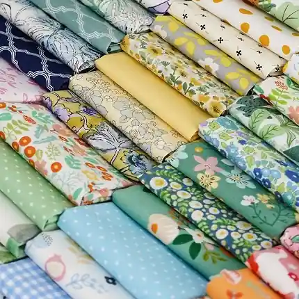 A collection of 100% cotton quilting fabrics in vibrant yellow, green, and blue color palettes.